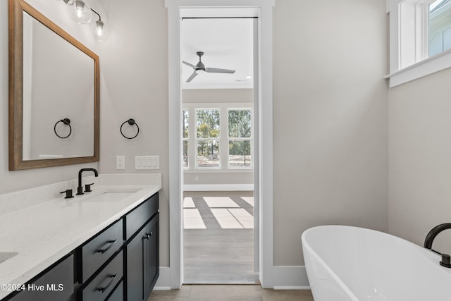 bathroom featuring ornamental molding, vanity, a tub, hardwood / wood-style floors, and ceiling fan