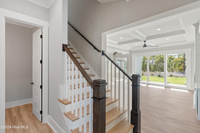 stairs featuring hardwood / wood-style floors, beamed ceiling, ceiling fan with notable chandelier, and coffered ceiling