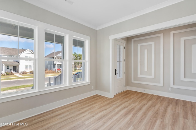 unfurnished room with ornamental molding and light wood-type flooring