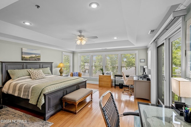 bedroom featuring ceiling fan, multiple windows, light hardwood / wood-style flooring, and a tray ceiling