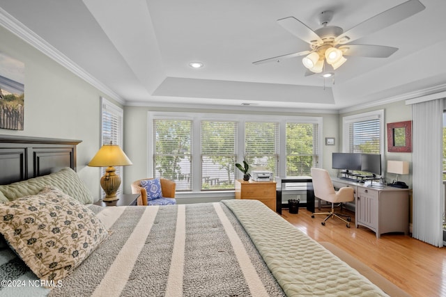 bedroom featuring ceiling fan, light hardwood / wood-style floors, a raised ceiling, and crown molding