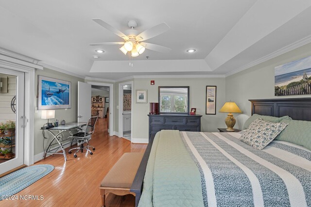 bedroom with ceiling fan, light hardwood / wood-style floors, ensuite bathroom, and a tray ceiling