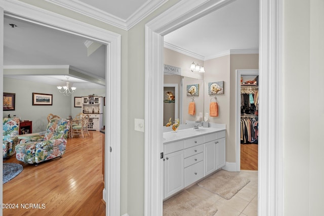 bathroom with tile patterned flooring, vanity, a notable chandelier, and ornamental molding