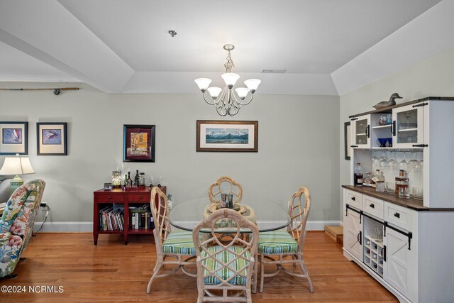 dining room with a chandelier, lofted ceiling, and light hardwood / wood-style floors