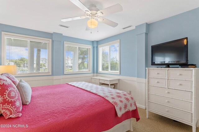 bedroom featuring ceiling fan, wood walls, and multiple windows