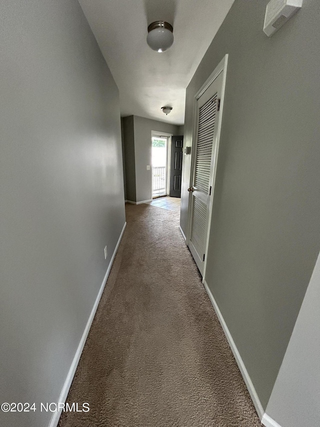 hall with carpet floors, visible vents, and baseboards