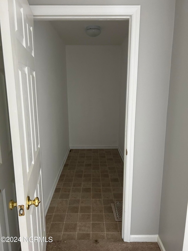 hall with dark tile flooring