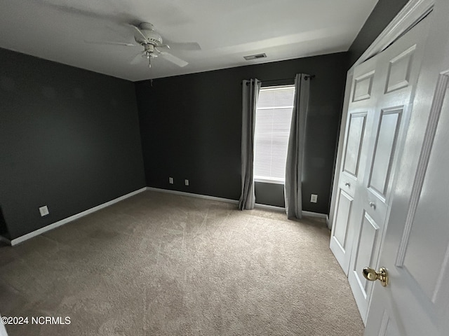 carpeted spare room with a ceiling fan, visible vents, and baseboards