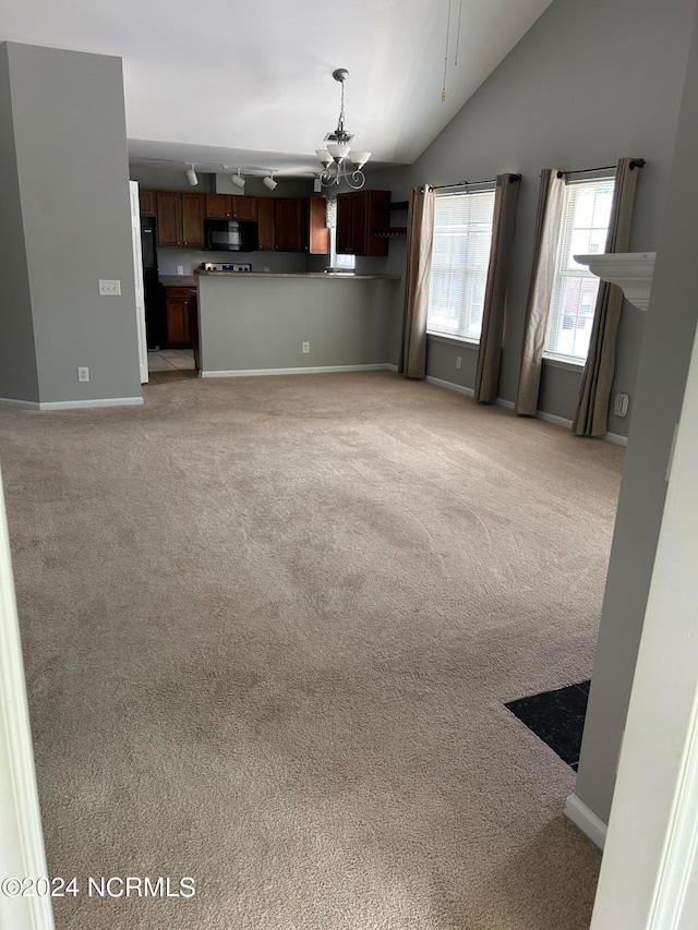 unfurnished living room with light colored carpet, vaulted ceiling, and an inviting chandelier