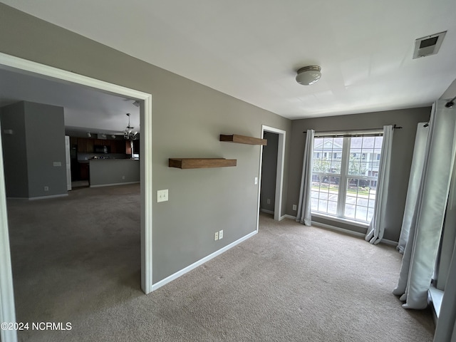 spare room with carpet flooring, visible vents, and baseboards