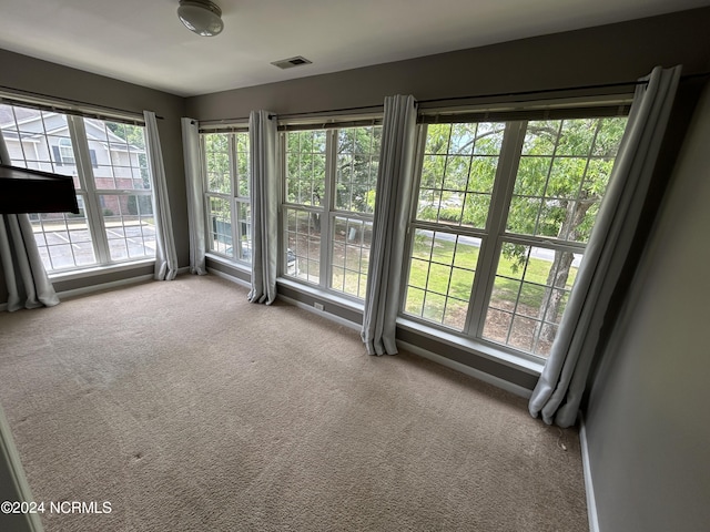 spare room with carpet, visible vents, and baseboards