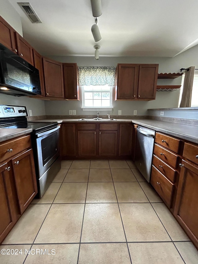 kitchen featuring stainless steel appliances, light tile floors, sink, and rail lighting