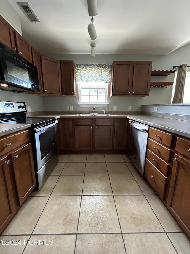 kitchen with light tile patterned floors, visible vents, dark countertops, stainless steel appliances, and a sink