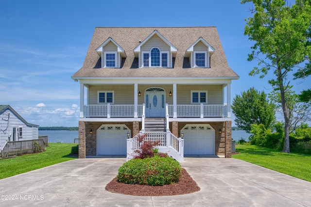 cape cod house featuring a porch, a garage, a water view, and a front lawn