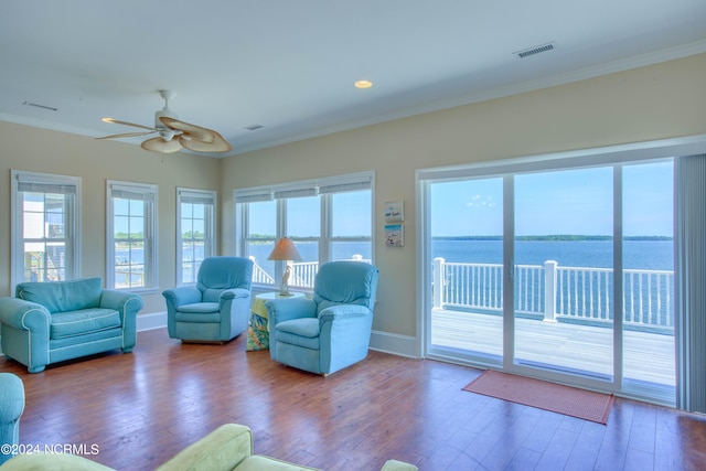 unfurnished living room featuring wood-type flooring, a water view, ceiling fan, and ornamental molding