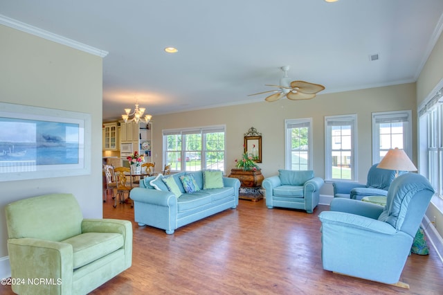 living room with wood-type flooring, ceiling fan with notable chandelier, and ornamental molding