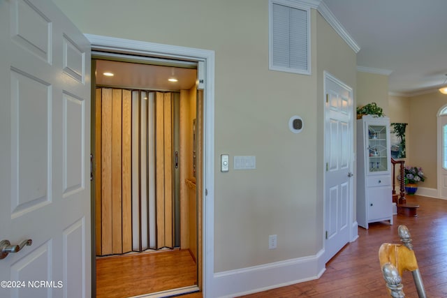 hallway featuring elevator, crown molding, and wood-type flooring