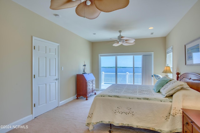 bedroom featuring access to exterior, light carpet, a water view, and ceiling fan