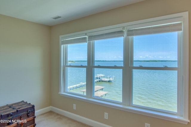 unfurnished room featuring carpet, a wealth of natural light, and a water view