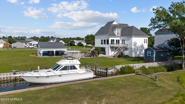 back of house featuring stairway, an outbuilding, a water view, a yard, and a shed