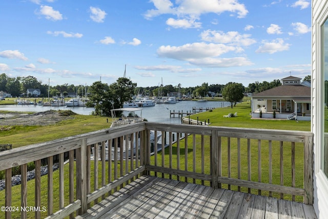 wooden deck with a lawn, a water view, and a boat dock