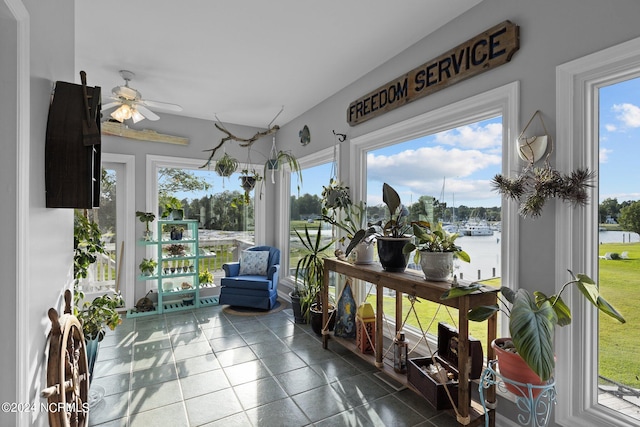 sunroom / solarium featuring a water view and ceiling fan