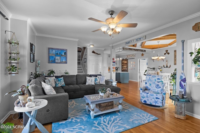 living room featuring plenty of natural light, wood-type flooring, ceiling fan with notable chandelier, and ornamental molding