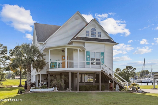 coastal inspired home with ceiling fan and a front lawn