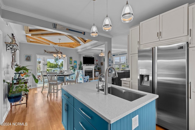 kitchen featuring pendant lighting, blue cabinets, sink, an island with sink, and high quality fridge