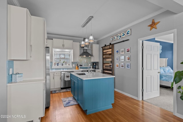 kitchen featuring appliances with stainless steel finishes, blue cabinets, sink, a barn door, and an island with sink