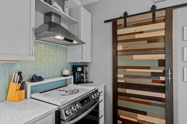 kitchen featuring electric range, wall chimney exhaust hood, a barn door, and white cabinets