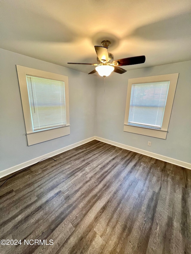 unfurnished room featuring dark wood-type flooring, a ceiling fan, and baseboards