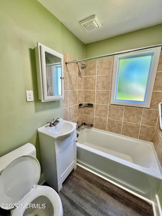 full bath featuring toilet, wood finished floors, vanity, visible vents, and  shower combination