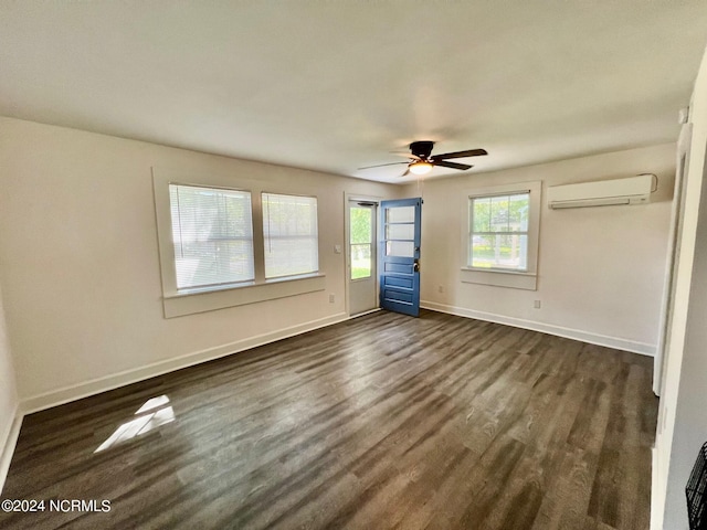 unfurnished bedroom featuring dark wood-style flooring, a wall unit AC, a ceiling fan, and baseboards