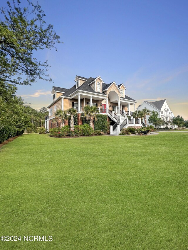 new england style home with covered porch and a front lawn