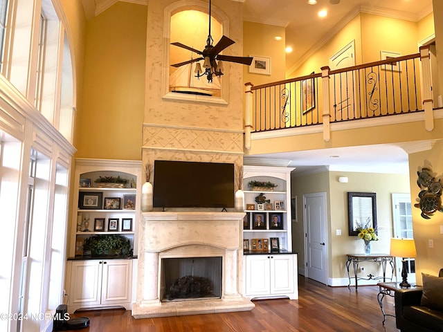 living room with hardwood / wood-style flooring, ornamental molding, ceiling fan, and a towering ceiling