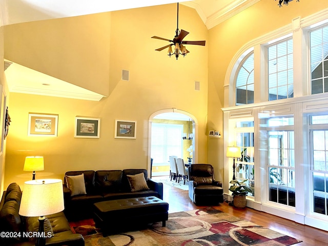 living room featuring wood-type flooring, crown molding, and plenty of natural light