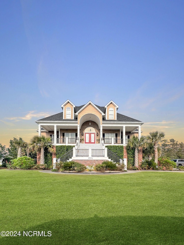 view of front of property featuring french doors, covered porch, and a lawn