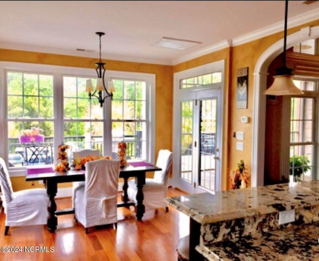 dining room with hardwood / wood-style flooring, crown molding, and an inviting chandelier