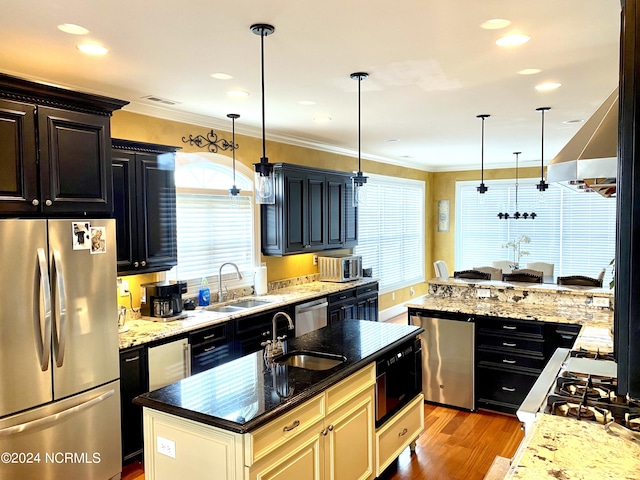 kitchen featuring sink, hanging light fixtures, stainless steel appliances, and a center island with sink