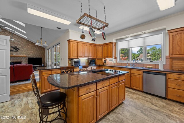 kitchen featuring a brick fireplace, a kitchen island, dishwasher, sink, and light tile floors