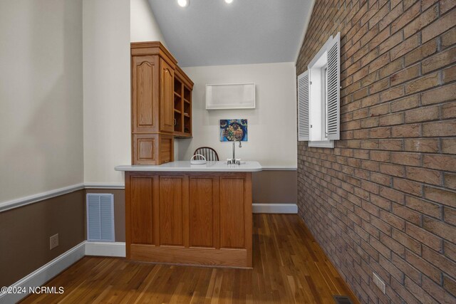 kitchen featuring dark hardwood / wood-style floors, kitchen peninsula, and brick wall