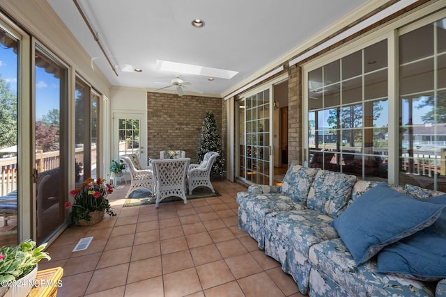 sunroom featuring a skylight, ceiling fan, and a wealth of natural light