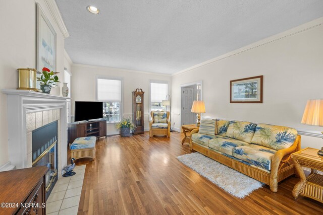 living room featuring light hardwood / wood-style floors, a tile fireplace, and crown molding