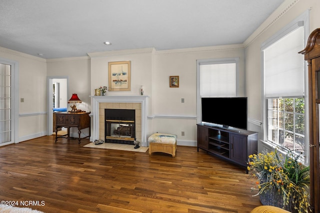 living room with dark hardwood / wood-style floors, a tile fireplace, and crown molding