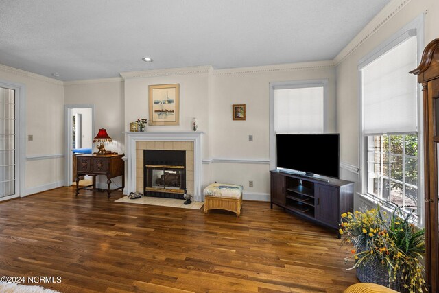 living room with crown molding, dark hardwood / wood-style flooring, and a tiled fireplace