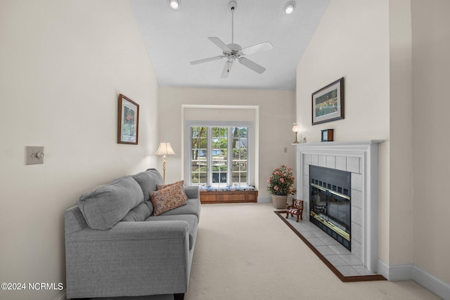 living room with high vaulted ceiling, a tiled fireplace, ceiling fan, and light colored carpet