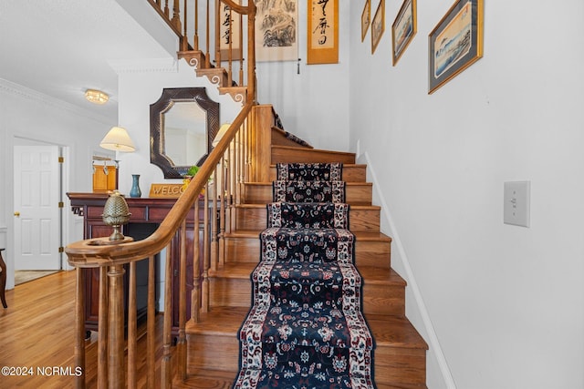 stairway featuring wood-type flooring and ornamental molding