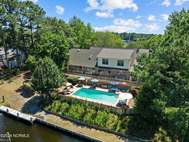 rear view of property with a water view, a patio area, and a fenced in pool