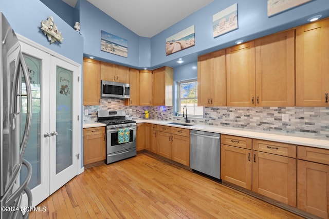 kitchen featuring light wood-style flooring, appliances with stainless steel finishes, a sink, and french doors